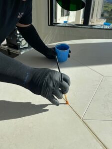 Close-up of a technician carefully applying AntiEtch® into the grooves of a limestone table using a fine brush.