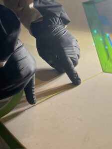 Technician applying pinstriping tape to the grooves on the outer edges of a limestone table to ensure precise AntiEtch® application.