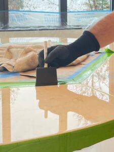 Technician using a detailing sponge to carefully remove excess AntiEtch® from the grooves of a limestone table, ensuring the grooves remain clean and defined.