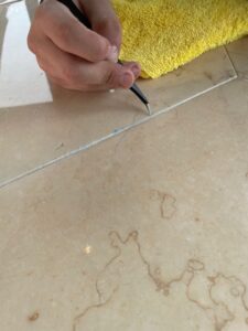 Close-up view of a technician carefully detailing the grooves of a limestone table, ensuring a precise and clean finish after AntiEtch® application.