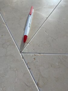 Top-down close-up of the limestone table, showing the V-grooves and natural holes that need filling, with a pen for scale.